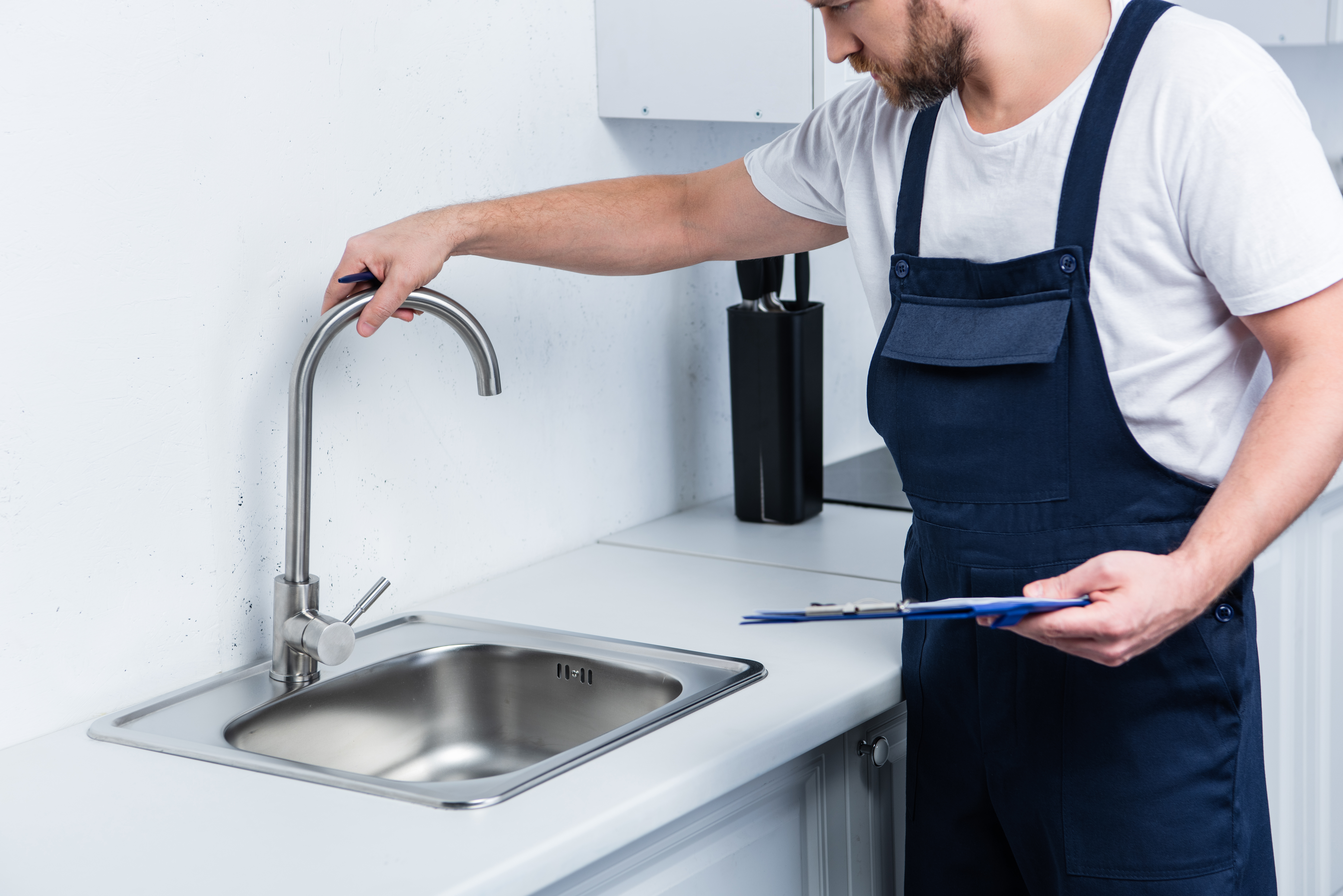 Plombier vérifiant un robinet de cuisine.