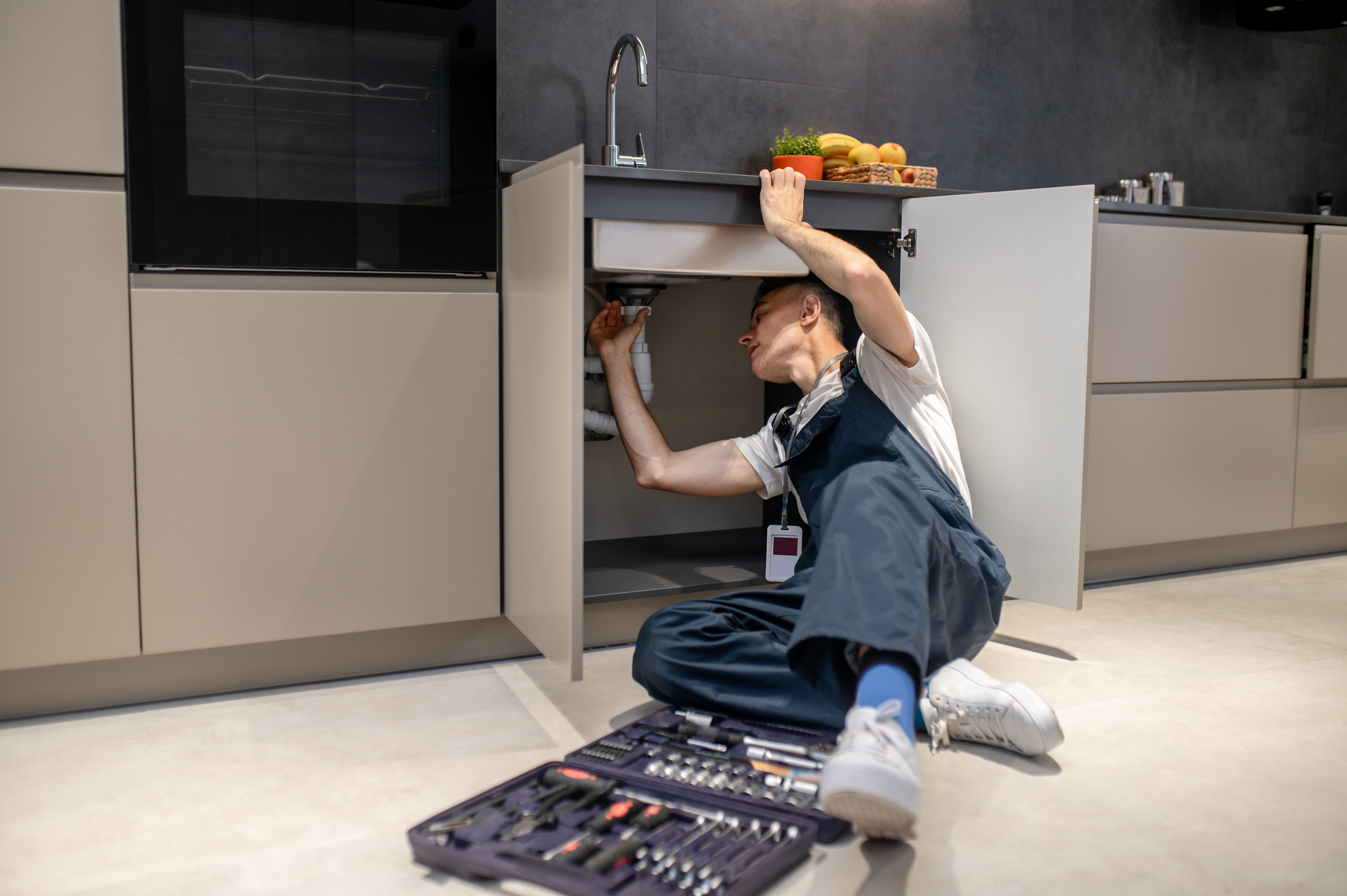 Plombier réparant un évier de cuisine.