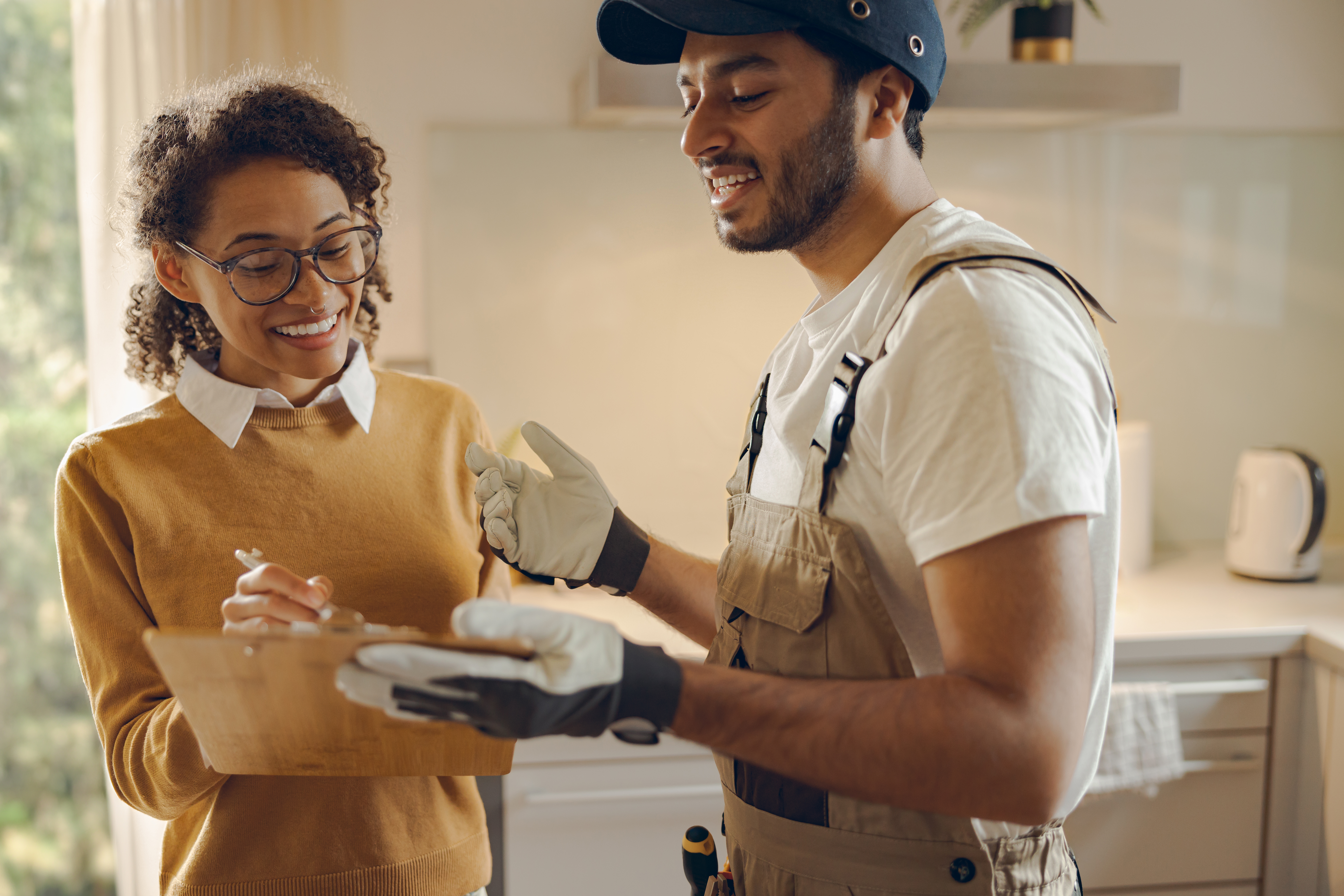 Discussion entre femme et artisan dans une cuisine.